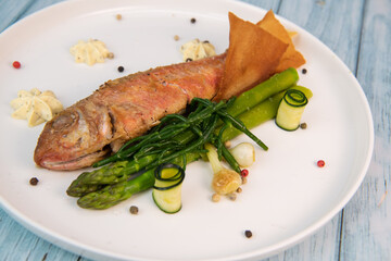 Plate of fried small fish red mullet with green asparagus. High quality photo