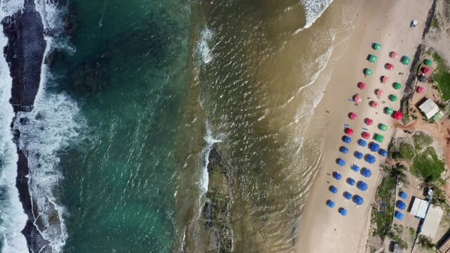 Aerial drone bird's eye top view shot of small waves crashing into a large rock creating natural pools for swimming on the famous tropical Sibauma beach in Tibau do Sul, Rio Grande do Norte, Brazil