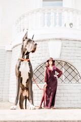 A photo of a woman and her Great Dane walking through a town, taking in the sights and sounds of...
