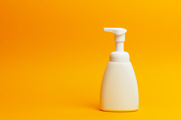 White gel dispenser bottle on orange background.