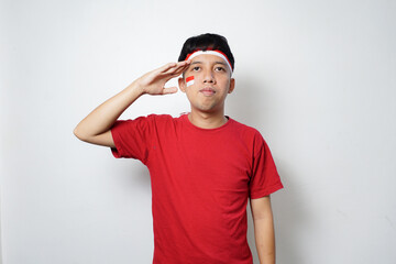 Fototapeta premium Excited young Asian man with attribute Indonesian flag while celebrating Indonesia's independence day