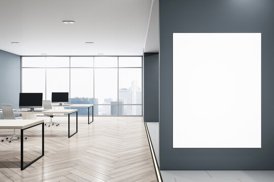 Front view on blank white poster on dark grey wall with space for your logo advertising in modern open space office with table and chairs on wooden floor. 3D rendering, mockup