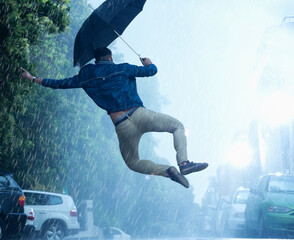 Man with umbrella jumping in rain