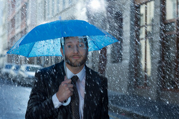Portrait of businessman with tiny umbrella in rain