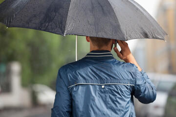 Man talking on cell phone under umbrella in rain
