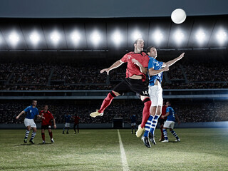 Soccer players jumping for ball on field