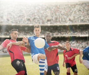 Obraz premium Soccer players reaching for ball on field