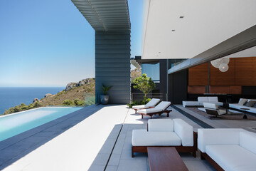 Lounge chairs and infinity pool on modern patio overlooking ocean