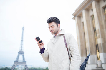 Fototapeta Businessman using cell phone by Eiffel Tower, Paris, France obraz