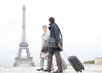 Business people with suitcases passing by Eiffel Tower, Paris, France