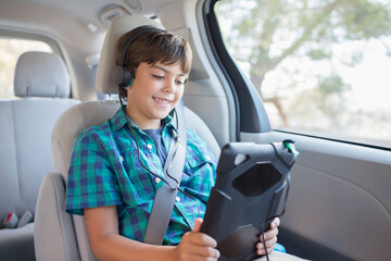 Happy boy using digital tablet in back seat of car