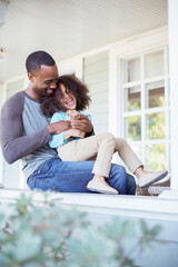 Father tickling daughter on porch