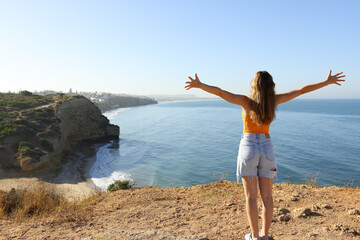 Excited woman celebrating vacation in a coast