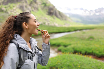 Hiker eating cereal bar in a valley - 607272671