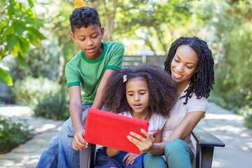 Mother and children using digital tablet outdoors