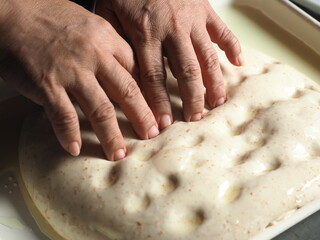 dimpling Focaccia bread dough with fingers