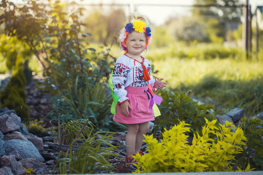 cheerful little girl in national Ukrainian clothes in a sunny summer garden