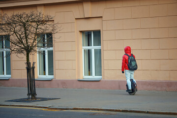 Man riding fast on electric unicycle on city street, commuting to work. Portable individual transportation vehicle. Man on electric monowheel (EUC). Stylish guy moves along sidewalk on mono wheel © Tricky Shark