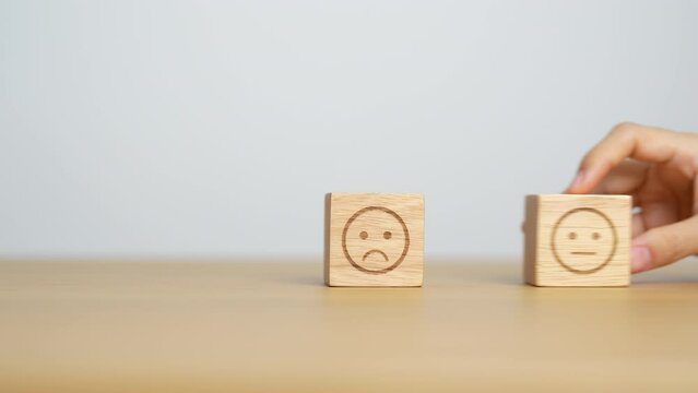 Hand choosing smile face from Emotion block for customer review, good experience, positive feedback, satisfaction, survey, evaluation, assessment, mood and world mental health day concept