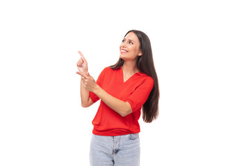 young european woman with black hair dressed in a red t-shirt shows empty space on the wall