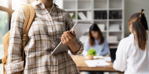 Close up of Young student with backpack carrying digital tablet in college. Student working at background. education, back to school concept