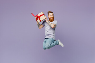 Full body amazed young redhead bearded man wear violet t-shirt casual clothes hold present box with...
