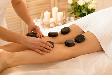 Woman getting a hot stone  massage therapy massage in spa salon 	