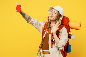 Young woman carry backpack with stuff mat do selfie shot mobile cell phone isolated on plain yellow...