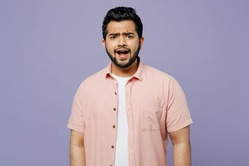 Young sad displeased dissatisfied disappointed Indian man he wear pink shirt white t-shirt casual clothes looking camera isolated on plain pastel purple background studio portrait. Lifestyle concept.