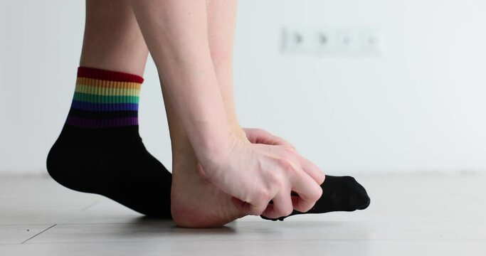 Woman puts on black socks with LGBT symbols. Fashion brands use LGBT colors in clothing