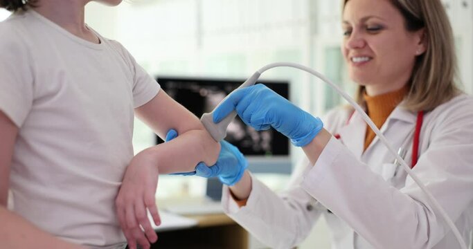 Traumatologist conducts ultrasound examination of child elbows in clinic. Bruised elbow in child signs symptoms and treatment