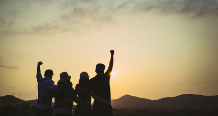 Fototapeta na wymiar group of people with raised arms looking at sunrise on the mountain background. Happiness, success, friendship and community concepts.