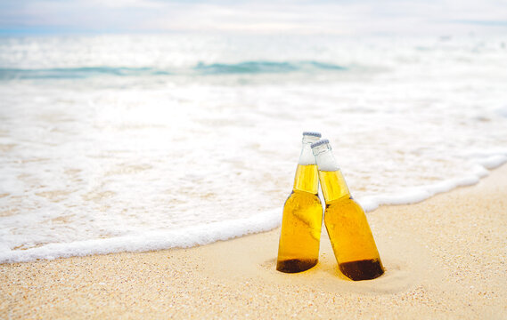Bottles of Beer on the sandy beach with sea ocean background. Party, Friendship, Beer Concept.