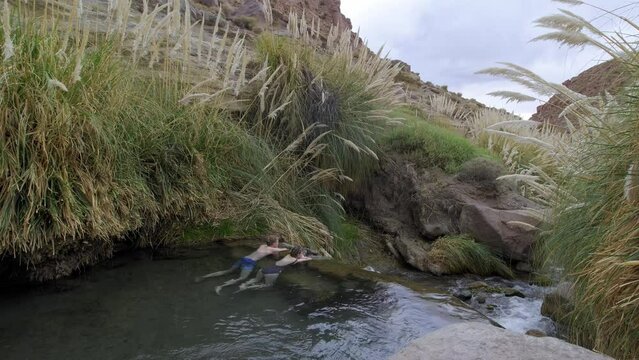 Wide Angle of Young Couple Relaxing by Tall Pampas Grass at the Puritama Hot Springs, High Altitude, Northern Chile.