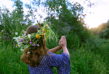 girl in flower wreath outdoor, abstract natural green background. rear view. Floral crown, symbol of summer solstice. ceremony for Midsummer, wiccan Litha sabbat. pagan folk holiday Ivan Kupala - obrazy, fototapety, plakaty