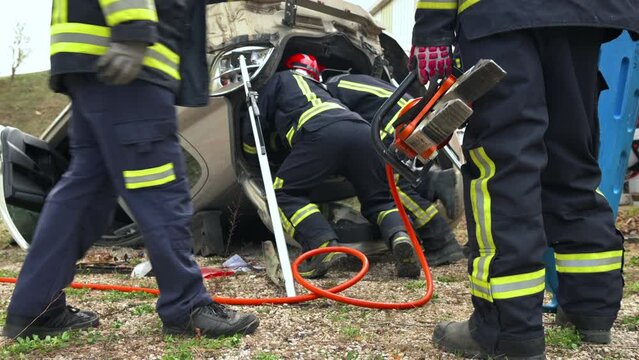 Firefighters using hydraulic tools during a rescue operation training. Rescuers unlock the passenger in car after accident. High quality 4k footage