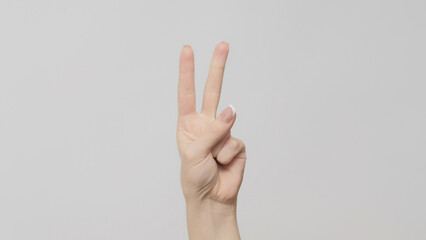 Hand gesture. Two number. Woman counting double fingers up on light gray background.
