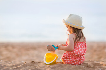 baby girl is sitting on beach and playing in sand in summer. holidays with children