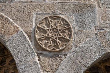 Detail of a geometric sculpture in the form of a rosette on a medieval wall in the Dordogne in France