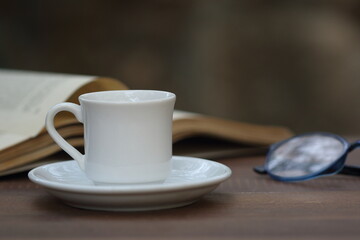 Cup of coffee on the table. Reading a book concept. 