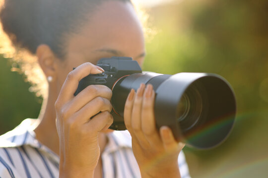 Black photographer taking pictures in a park - Powered by Adobe