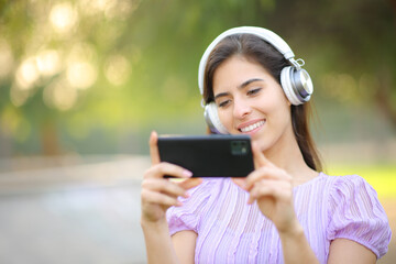 Happy woman with headphone watching videos on phone