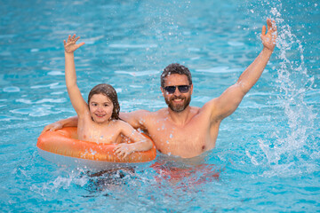 Father and son swimming in pool, summer family weekeng. Father and son splash water in pool on summer family holiday. Dad and child relaxing in pool water. Child with dad swimming in pool.