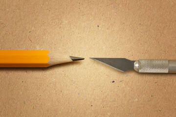 Sharpened pencil versus blade of craft knife on recycled paper background - Concept of precision...
