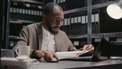 Male inspector reading witness statements and clues to find suspect, using case files and...