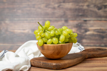 Green grapes in bowl. Organic farm products. Fresh bunch of grapes on wooden background