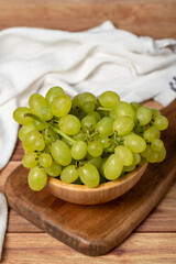 Green grapes in bowl. Organic farm products. Fresh bunch of grapes on wooden background. Close up