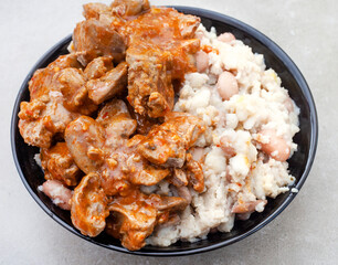 Traditional South African Peri Peri chicken livers with samp and beans on grey