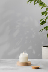 Obraz na płótnie Canvas A burning white interior candle in a glass cup. The concept of home decor, comfort. Handmade candle