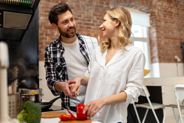 Happy couple cooking dinner together in kitchenn at home preparing vegetable salad.